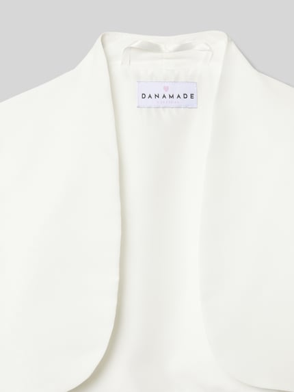 Produktfoto, weißer Kinder Bolero mit Stehkragen von DANAMADE, glatte Textur, dezente Struktur, Detailaufnahme des Kragens