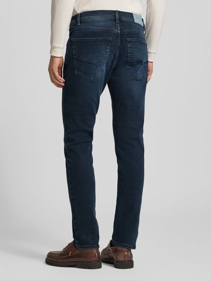 Männermodel trägt Straight Fit Jeans aus elastischem Baumwoll-Mix Modell 'Lyon' von Pierre Cardin in Dunkelblau, Ganzkörperansicht Rückansicht. 5-Pocket-Design, Gürtelschlaufen, Knopf- und Reißverschluss. Bundweite und Innenbeinlänge Größe 32/32 laut Kontext.