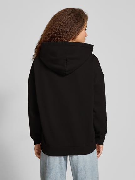 Frauenmodel trägt Oversized Hoodie mit Label-Stitching Modell 'CLARITA' von Pegador, schwarz, Baumwoll-Mix, Ganzkörperansicht Rückansicht.