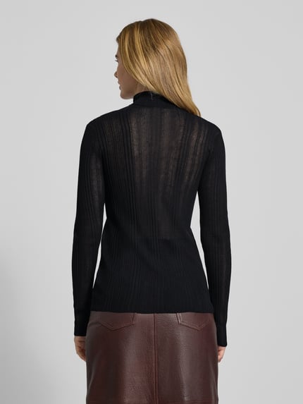 Frauenmodel trägt schwarzen Strickpullover mit Rollkragen Modell 'Haddis' von My Essential Wardrobe, Viskose-Mix, semitransparent, Ganzkörperansicht Rückansicht.