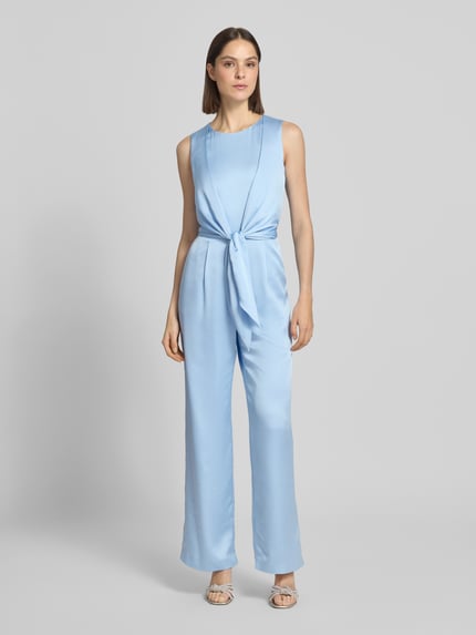 Frauenmodel trägt Jumpsuit aus Satin mit Bindegürtel von Christian Berg Cocktail in Hellblau, leicht tailliert, Ganzkörperansicht von vorne.