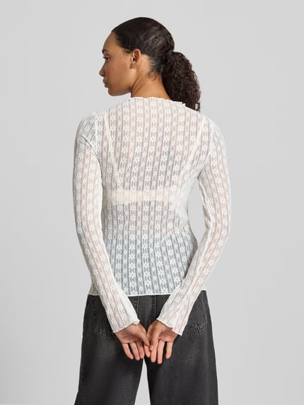 Vrouwenmodel draagt transparant wit shirt met lange mouwen Model 'Zahara' van OH APRIL, materiaalmix met stretch, slim fit, ronde hals, labeldetail, ruglengte maat S 63 cm, volledige lichaamsopname achteraan.