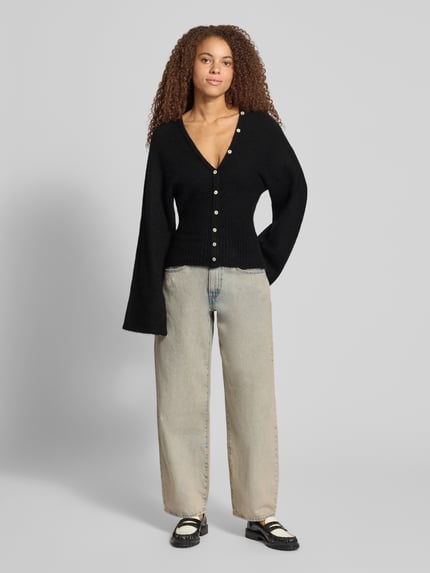 Vrouwenmodel draagt Regular Fit gebreid jack met wol van Gina Tricot, zwarte kleur, ribboorden, knoopsluiting, elastische materiaalmix, Met lange mouwen, Ruglengte maat S 53 cm, Mouwlengte maat S 49 cm, effen design, regular fit, Ganzkörperansicht van voren.