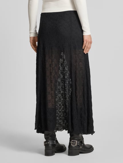 Frauenmodel trägt Maxirock mit Spitze und elastischem Bund von Review, A-Linie, schwarzer Material-Mix, blickdichtes Innenfutter, Ganzkörperansicht Rückansicht.