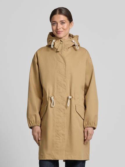 Kobiece modelka nosi Regular Fit Mantel mit durchgängiger Abdeckleiste Modell 'Tory' od G-LAB, beżowy bawełniany miks, kaptur, stójka, zamek, kieszenie, elastyczne mankiety, długość tyłu 96 cm, szerokość ramion 49 cm, szerokość w rozmiarze S 54 cm, długość rękawa 53 cm, całkowity widok z przodu.