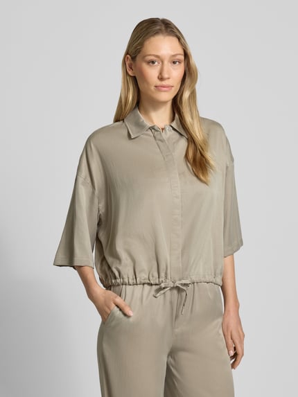Modelka nosi Relaxed Fit Bluzkę z mieszanki modalu model 'Lainay' od Drykorn, kolor beżowy, półrękaw, tunel w dole, widok z przodu, zbliżenie na górną część ciała.