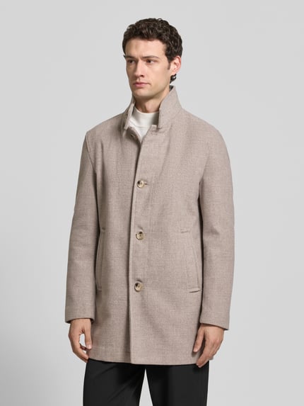 Männermodel trägt Daunenjacke Modell 'Fynn' mit Stehkragen von Strellson, unifarben matt beige, Struktur, Knopfleiste, seitliche Eingrifftaschen, Ganzkörperansicht von vorne.