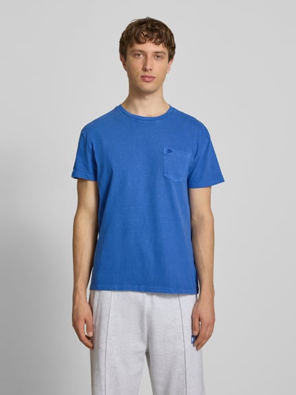 Männermodel trägt T-Shirt aus Baumwoll-Leinen-Mix mit Brusttasche von Superdry in Blau, Regular-Fit, Rundhalsausschnitt, Rückenlänge 66 cm, Ganzkörperansicht von vorne.