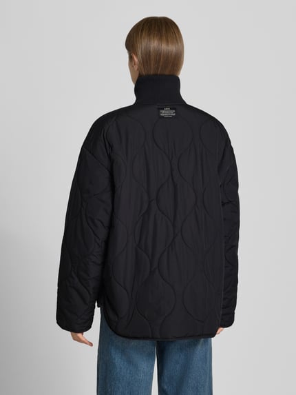 Vrouwenmodel draagt gewatteerd jack met doorgestikte naden, opstaande gebreide kraag, ritssluiting, steekzakken, Model 'SERENA' van JJXX, loose fit, zwart, ruglengte maat S 89 cm, schouderbreedte 58 cm, borstwijdte 57 cm, mouwlengte 55 cm, achterkant, Ganzkörperansicht Rückansicht.