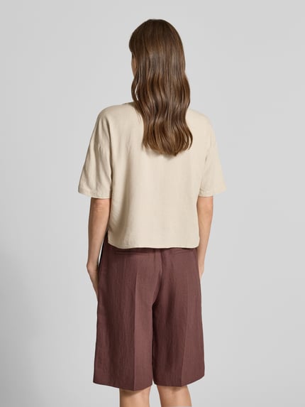 Männermodel trägt bluzka koszulowa Boxy Fit Hemdbluse aus Viskose-Leinen-Mix Modell 'MYMILO' von Vero Moda, kolor beżowy, cieniowana przędza, rękaw o dł. 3/4, dekolt w serek, tunika, wykończenie materiału: mieszanka wiskozy i lnu, Ganzkörperansicht Rückansicht.