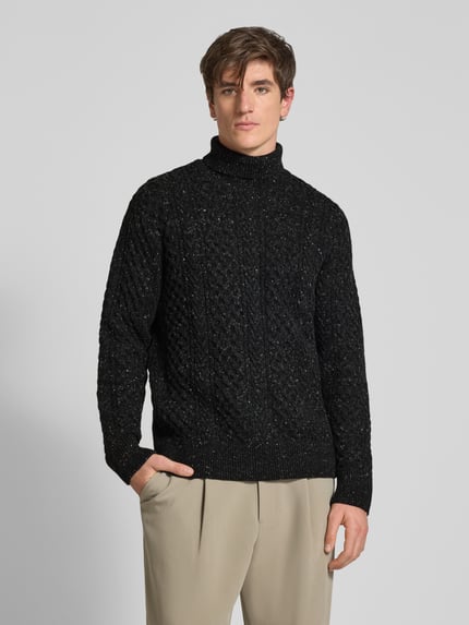 Männermodel trägt Rollkragenpullover mit Zopfmuster-Struktur von Selected Homme in Melange-Strickoptik, Ganzkörperansicht von vorne.
