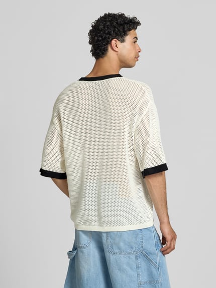 Männermodel trägt T-Shirt in Häkel-Optik mit V-Ausschnitt von KARL KANI, Baumwoll-Mix, Loose-Fit, Label-Stitching, Rückansicht, Rückenlänge 68 cm bei Größe M.