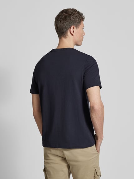Męski model nosi Regular Fit T-Shirt aus reiner Baumwolle von camel active, okrągły dekolt, nadruk z napisem, krój regular fit, długość tyłu w rozmiarze M: 68 cm, ciemnogranatowy kolor, widok całej sylwetki z tyłu.
