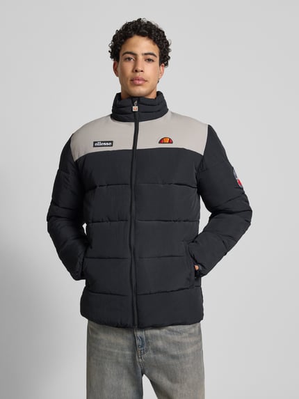 Mannelijk model draagt Steppjacke met rits model 'NEBULA' van Ellesse in zwart en grijs, labeldetails, steekzakken, voorkant volledige lichaamsaanzicht.