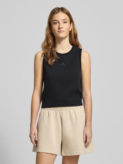 Frauenmodel trägt Regular Fit Top mit Logo-Print von adidas Sportswear in Schwarz, elastischer Material-Mix, Rundhalsausschnitt, Ganzkörperansicht von vorne.