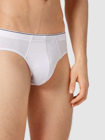 Männermodel trägt Slip mit elastischem Bund im 3er-Pack von MCNEAL aus weißem Baumwoll-Elasthan-Mix, körpernaher Schnitt, Nahaufnahme Oberkörper.