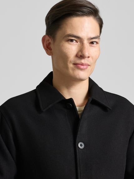 Männermodel trägt Jacke mit Umlegekragen und Knopfleiste Modell 'CAVE' von Forét, Schwarz, Baumwoll-Mix, Nahaufnahme Oberkörper.
