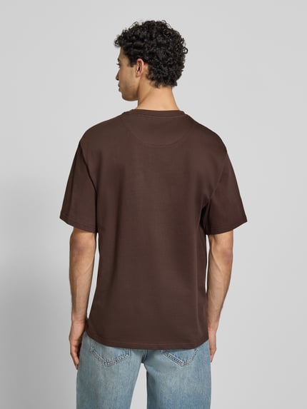 Männermodel trägt Regular Fit T-shirt mit gestikt logo von KARL KANI, ronde hals, met korte mouwen, ruglengte maat M 74 cm, Ganzkörperansicht Rückansicht