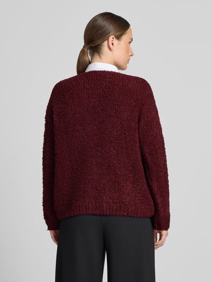 Frauenmodel trägt Relaxed Fit Strickjacke aus Woll-Viskose-Mix Modell 'Sofia' von ZABAIONE in Dunkelrot, strukturierte Oberfläche, Ganzkörperansicht Rückansicht. Damen Strickjacke, durchgängige Knopfleiste, langärmliges Design, V-Ausschnitt, Rückenlänge 62 cm, Ärmellänge 45 cm.