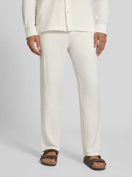 Männermodel trägt Straight Fit Sweatpants in Musselin-Optik von Lindbergh aus Reine Baumwolle, helle Farbe, strukturierte Oberfläche, Ganzkörperansicht von vorne. Bundweite Größe M 41 cm, Innenbeinlänge 81 cm, elastischer Bund mit Tunnelzug.
