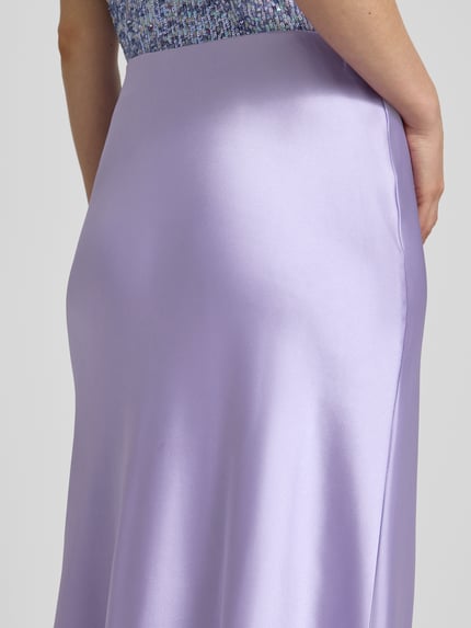 Vrouwenmodel draagt Midirock aus Satin Modell 'Fabiola' van GUIDO MARIA KRETSCHMER WOMAN in lila, satijnen textuur, nauwsluitende fit, elastische mix, detailopname heupen.