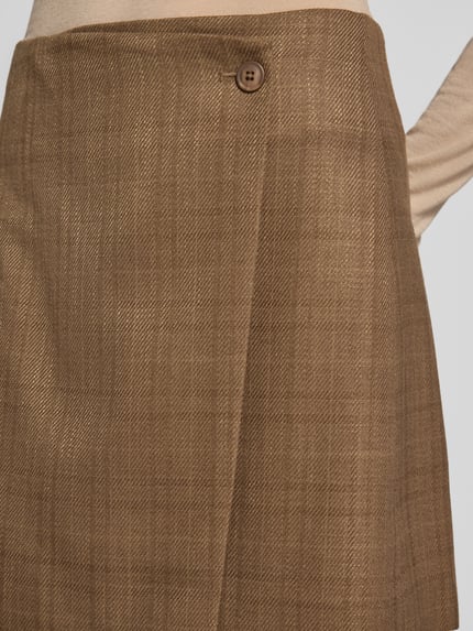 Frauenmodel trägt Minirock in Wickel-Optik Modell 'Kanille' von mbyM, Braun mit feinem Karomuster, Viskose-Mix, Nahaufnahme Oberkörper.