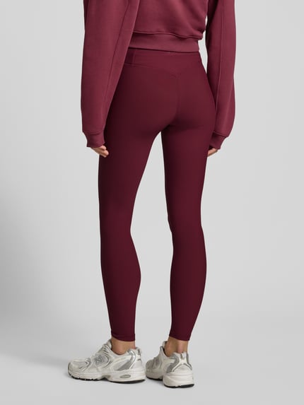 Frauenmodel trägt Leggings mit elastischem Bund Modell 'Cherry Ribbed Performance' von AIMN in Dunkelrot, fein gerippte Textur, Körpernahe Passform, Material-Mix mit Stretch-Anteil, Ganzkörperansicht Rückansicht.