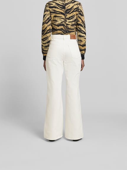 Vrouwenmodel draagt Flared Fit Jeans met klepzakken van ROTATE, puur katoen, flared fit, achterzakken, knoop- en ritssluiting, binnenbeenlengte maat 32: 85 cm, bandwijdte maat 32: 41 cm, jeans voor dames, volledig aanzicht achterkant.