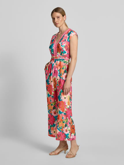 Kobiece model nosi Jumpsuit im Allover-Look mit Knotendetail od ROBE LÉGÈRE, krój regular fit, kolorowy wzór, materiał z domieszką stretchu, dekolt V, pasek w talii, długość pleców w rozmiarze 36: 139 cm, szerokość w rozmiarze 36: 52 cm, całkowita długość w rozmiarze 36: 139 cm, długość nogawki wewnętrznej w rozmiarze 36: 68 cm, widok całej sylwetki z przodu.