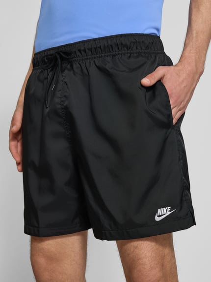 Männermodel trägt Shorts mit Label-Stitching und elastischem Bund von Nike, Regular-Fit in Schwarz mit Tunnelzug, Nahaufnahme Oberkörper. Kontext: Herren Shorts mit Bundweite 41 cm und Innenbeinlänge 14 cm bei Größe M.