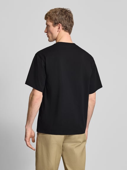 Männermodel trägt T-Shirt mit Label-Detail und Rundhalsausschnitt von Dickies, czarna bawełna, krój relaxed fit, długość pleców M: 70 cm, Ganzkörperansicht Rückansicht.