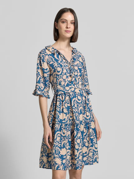 Vrouwenmodel draagt Knielanges Kleid aus Viskose im Allover-Look van Christian Berg Woman in blauw-beige met volants, strikceintuur, V-hals, A-lijn, knielengte, zuiver viscose, all-over look, ruglengte 100 cm, borstwijdte 34 cm, mouwlengte 32 cm, Ganzkörperansicht van voren.