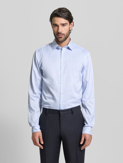 Männermodel trägt Slim Fit Business-Hemd mit Kentkragen von Jake*s, hellblau gestreift, Elastischer-Material-Mix, Ganzkörperansicht von vorne.