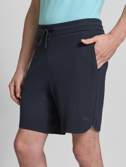 Mężczyzna nosi Regular Fit Stoffshorts aus Viskose-Mix model 'KN_UNION SH' od BOSS Green, ciemny kolor, ziarnista faktura, zbliżenie górnej części nogawek, zdjęcie z przodu.
