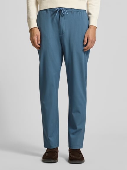 Männermodel trägt Stoffhose mit elastischem Bund von MCNEAL in Blau, Material-Mix mit Viskose-Anteil, lockerer Schnitt, Ganzkörperansicht von vorne.