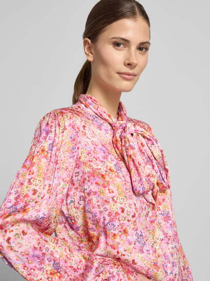 Frauenmodel trägt Relaxed Fit Hemdbluse aus reiner Viskose von Rich & Royal, floraler Print, Zierschleife, Nahaufnahme Oberkörper.