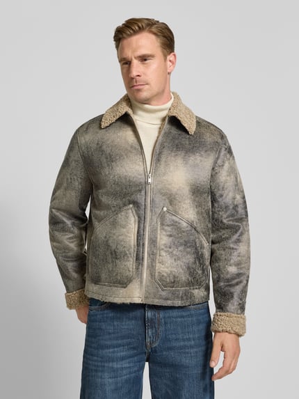 Männermodel trägt Jacke mit Kentkragen Modell 'LERON' von DRYKORN, gerader Schnitt, Teddyfell, Reißverschluss, Jeans, Ganzkörperansicht von vorne.