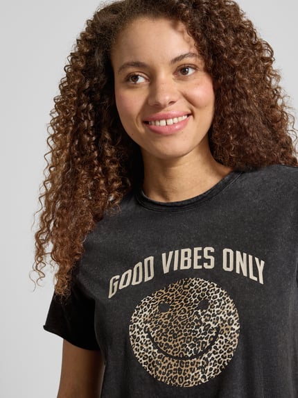 Frauenmodel trägt Regular Fit T-Shirt aus reiner Baumwolle Modell 'LISA LIFE LUCY' von Only, unifarben, Motiv-Print, Nahaufnahme Oberkörper.