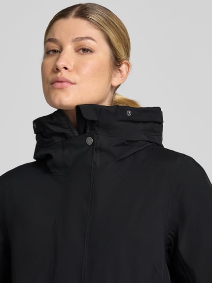 Frauenmodel trägt Regular Fit Parka mit Kunstfellbesatz Modell 'ERNA' von Didriksons in Schwarz, glatte Oberfläche, Nahaufnahme Oberkörper. Damen Parka mit Thermore Füllung, 10.000mm Wassersäule, Kapuze, Rückenlänge 93 cm, Schulterbreite 42 cm, Brustweite 51 cm, Ärmellänge 66 cm.