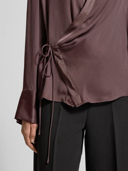 Frauenmodel trägt Hemdbluse mit Schnürverschluss von Mango in Wickel-Optik, Lockere-Schnitt und Hemdblusenkragen, Nahaufnahme Oberkörper.