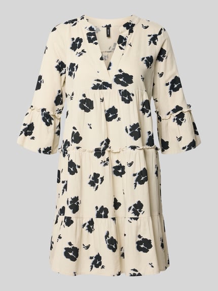 Produktfoto, Ausgestelltes Blusenkleid aus reiner Baumwolle Modell 'DICTHE' von Vero Moda in Creme mit schwarzem Allover-Muster, Mini-Länge, Raffung, Henley-Ausschnitt, halblange Trompetenärmel, strukturierte Textur