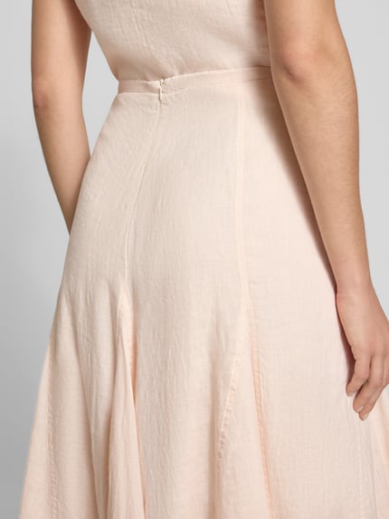 Vrouwenmodel draagt Leinenrock in A-linie met deelnaden van Emily Van den Bergh, zuiver linnen, midirok, detailopname rugaanzicht.