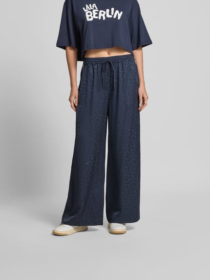 Frauenmodel trägt Wide Fit Sweatpants mit Viskose-Anteil von Lala Berlin, dunkelblau mit Allover-Animal-Print, Ganzkörperansicht von vorne.