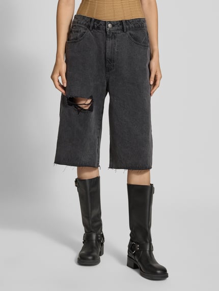 Frauenmodel trägt Jeansshorts im Destroyed-Look von Karo Kauer in Schwarz mit Cut Out, Eingrifftaschen, lockere Passform, Nahaufnahme Oberkörper. Damen Jeansshorts von Karo Kauer, Relaxed Fit, Bundweite bei Größe S: 41 cm, Innenbeinlänge bei Größe S: 37 cm.