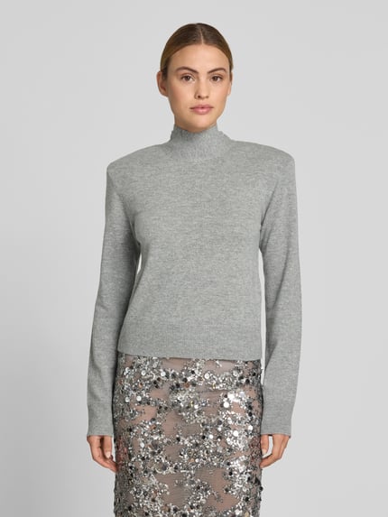 Modelka nosi Regular Fit Pullover aus Woll-Mix von ROTATE, kolor szary, imitacja dzianiny, golf, poduszki na ramionach, długość tyłu 50 cm, mieszanka wełny z kaszmirem, krój regular fit, widok całej sylwetki z przodu.