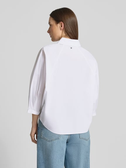 Frauenmodel trägt weiße Oversized Hemdbluse aus reiner Baumwolle Modell 'BELENTA' von BOSS Orange, Ganzkörperansicht Rückansicht