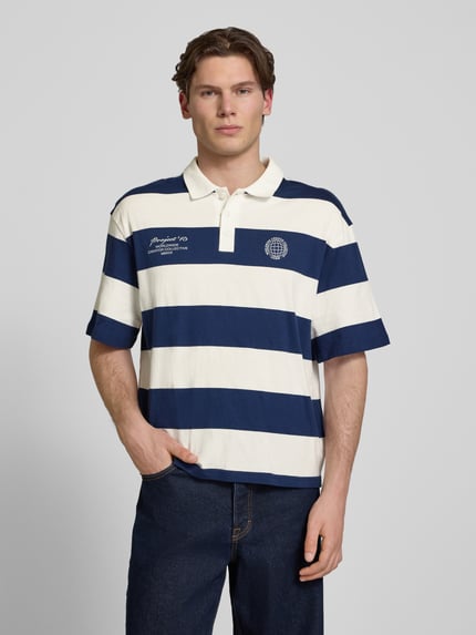 Männermodel trägt Relaxed Fit Poloshirt aus reiner Baumwolle Modell 'DEVIN' von Only & Sons, gestreift, kurzarm, Jersey, Ganzkörperansicht von vorne.