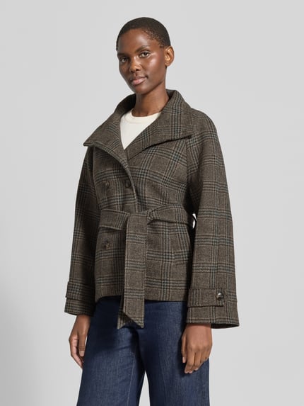 Frauenmodel trägt Jacke mit Stehkragen und Bindegürtel Modell 'Munet' von Neo Noir in Woll-Materialmix, Zweireiher, Karomuster, Ganzkörperansicht von vorne.