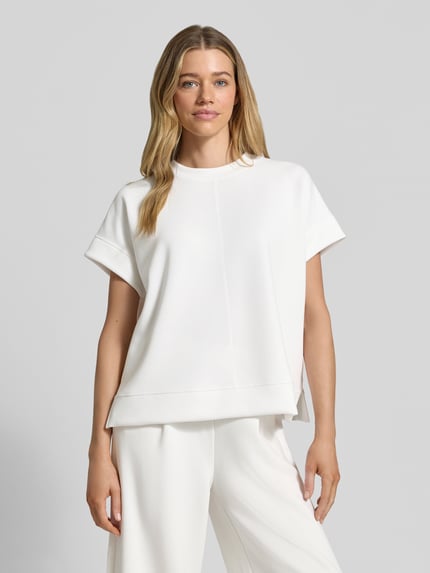 Frauenmodel trägt Relaxed Fit T-Shirt aus Modal-Mix von s.Oliver RED LABEL in Unifarbe Weiß, Rundhalsausschnitt, Kurzarm, Scuba-Material, mit Seitenschlitzen, Ganzkörperansicht von vorne.