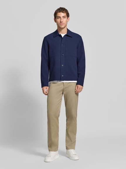 Männermodel trägt Regular Fit Hemdjacke mit Viskose-Anteil von Jake*s Studio Men in Dunkelblau, helle Hose, weiße Sneaker, Ganzkörperansicht von vorne.